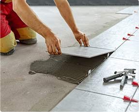 Stock image of a man setting tiles on floor